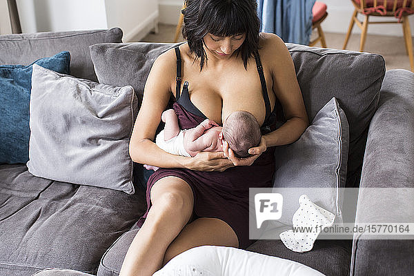 Mutter  die ihr neugeborenes Kind auf dem Sofa stillt