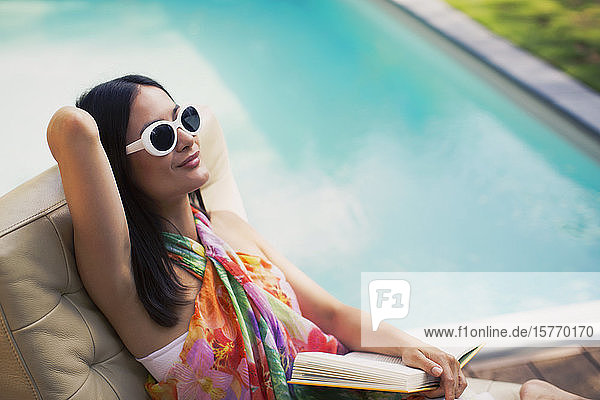 Serene woman relaxing reading book at summer poolside