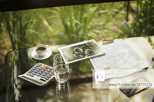 Taschenrechner und digitales Tablet auf dem Tisch mit Kaffee und Papierkram
