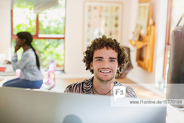 Portrait happy young man working from home at computer