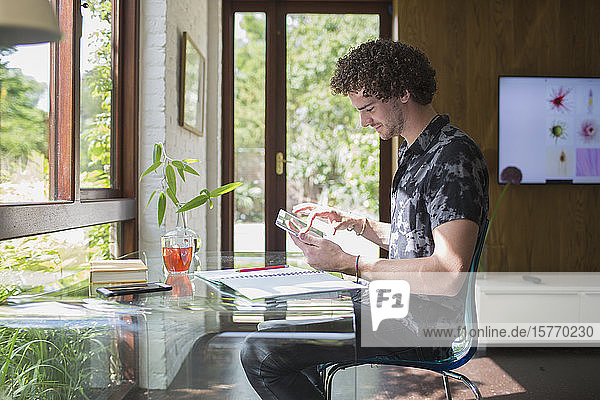 Junger Mann mit digitalem Tablet bei der Arbeit im Heimbüro