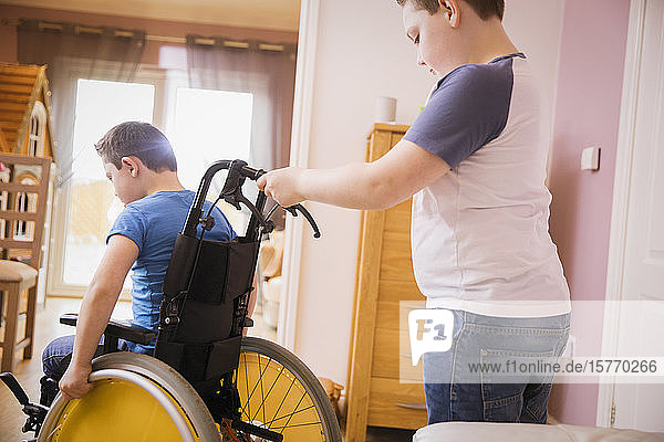 Junge schiebt Bruder im Rollstuhl