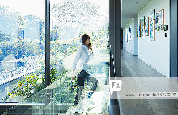 Frau beim Treppensteigen in einem sonnigen  modernen Luxushaus