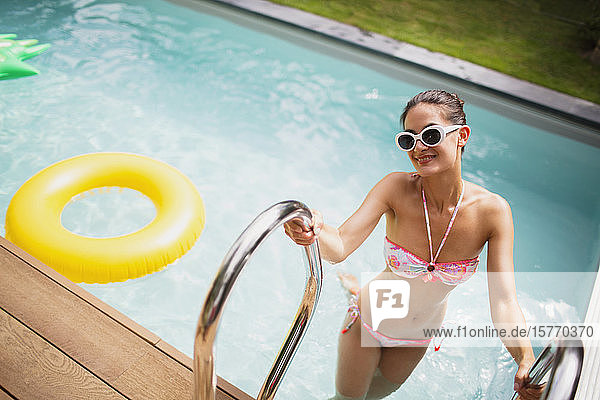 Portrait confident woman in bikini getting out of sunny summer swimming pool
