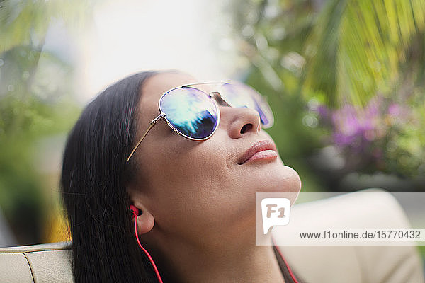 Close up heitere Frau mit Sonnenbrille beim Sonnenbaden  Musik hören mit Kopfhörern