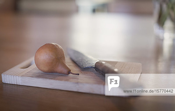 Still life knife and pear on wooden cutting board