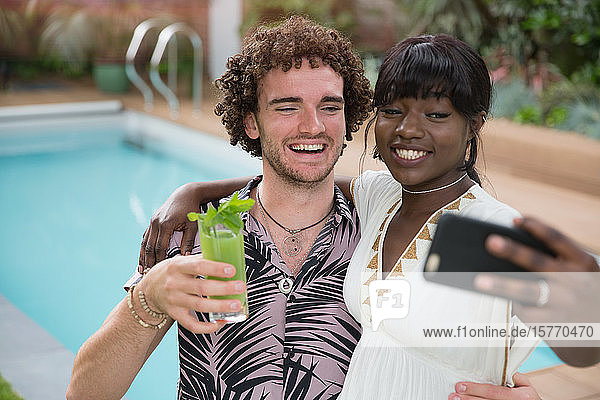 Glückliches junges Paar nimmt Selfie mit Kamera-Handy am Pool