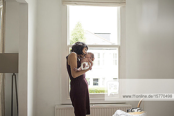 Mutter küsst neugeborenen Sohn im Fenster