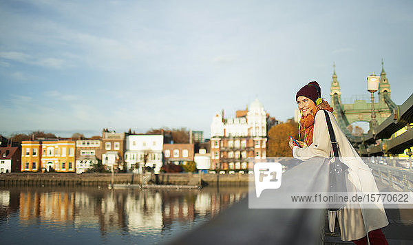 Junge Frau in Strumpfmütze und Schal auf städtischer Herbstbrücke