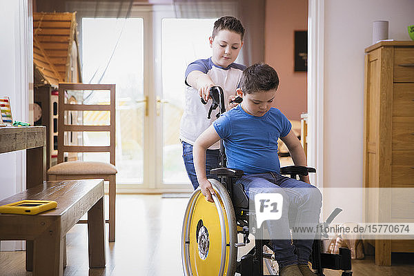 Junge schiebt seinen Bruder mit Down-Syndrom im Rollstuhl