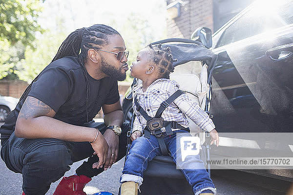 Zärtlicher Vater küsst sein Kleinkind im Kinderwagen