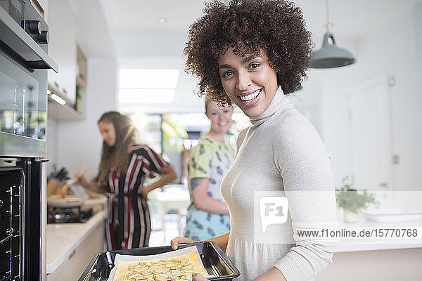 Portrait glückliche junge Frau beim Kochen mit Freunden in der Küche