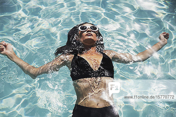 Serene Frau in schwarzem Bikini schwimmt im sonnigen Sommer Schwimmbad