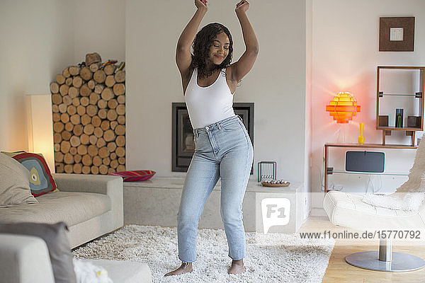 Unbekümmerte junge Frau tanzt im Wohnzimmer