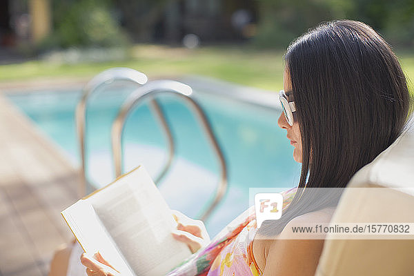 Frau liest Buch am sonnigen Sommerpool