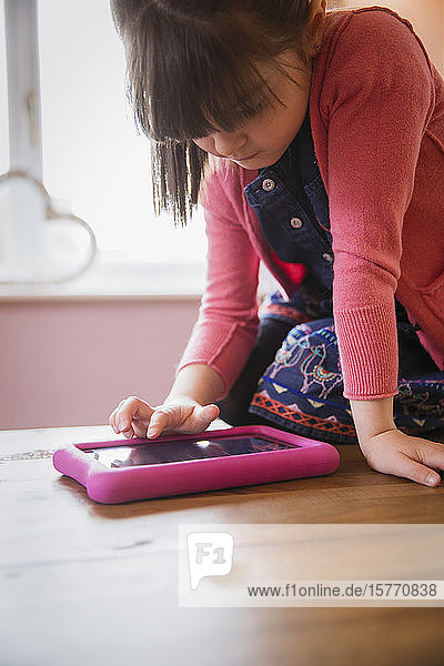 Mädchen benutzt digitales Tablet am Tisch