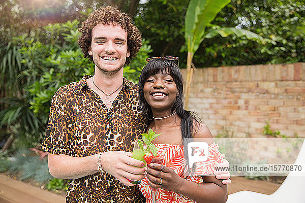 Portrait glückliches multiethnisches Paar trinkt Cocktails auf der Terrasse
