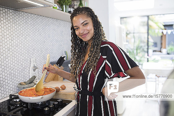 Porträt glückliche junge Frau beim Kochen am Herd in der Küche