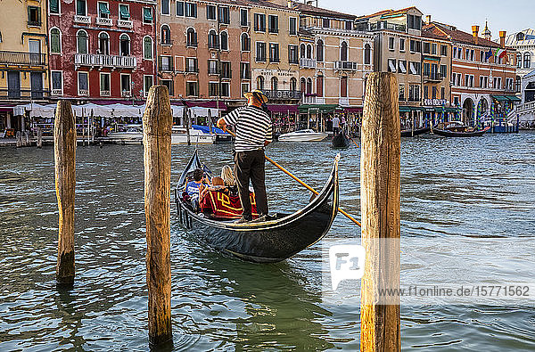 Gondeln und Gondoliere auf dem Canal Grande mit Touristen entlang der bunten Uferpromenade; Venedig  Italien