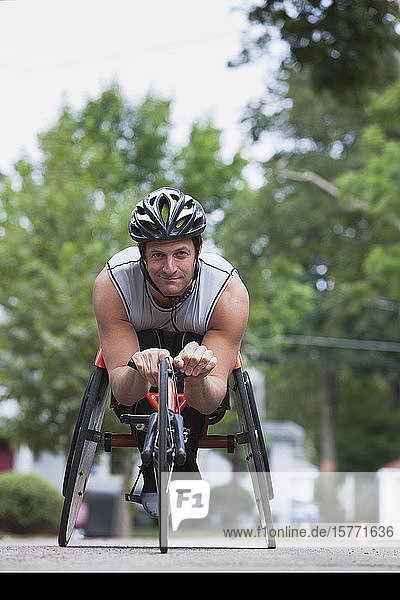 Disabled man with muscular arms sits in cycling equipment and looks at the camera