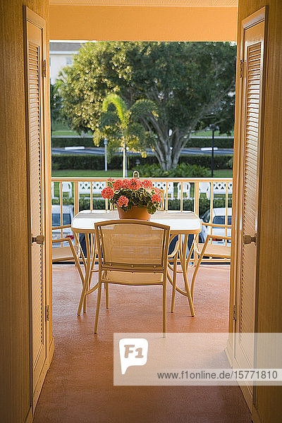 Blumentopf auf einem Tisch mit Stühlen in einem Innenhof einer Ferienanlage