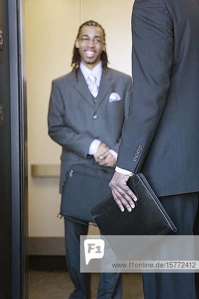 Ein junger Geschäftsmann lächelt in einem Aufzug.