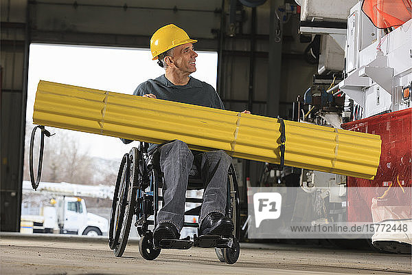 Ein behinderter Arbeiter transportiert Material in einer Werkstatt