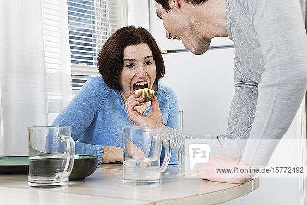 Blick auf ein halbwüchsiges Paar  das am Esstisch einen Muffin isst.