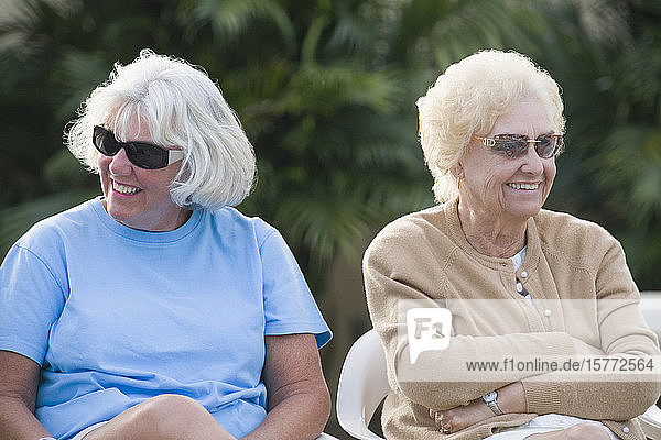 Zwei ältere Frauen sitzen zusammen und lächeln