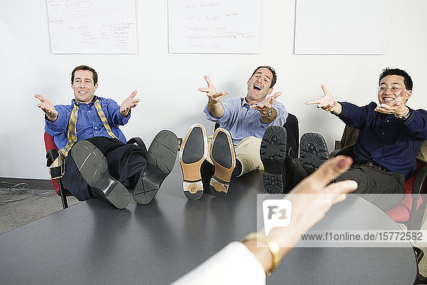 Geschäftsleute gestikulieren mit den Füßen auf dem Schreibtisch.