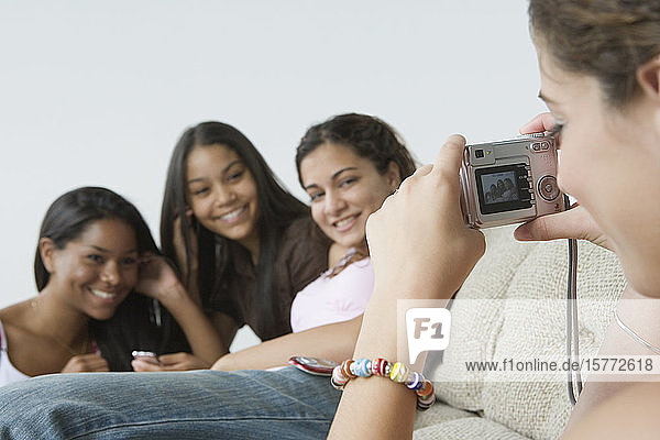Nahaufnahme eines Mädchens im Teenageralter  das ihre Freunde mit einer Digitalkamera fotografiert