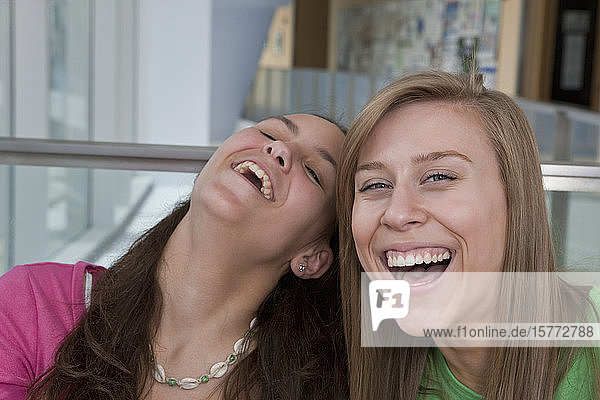 Zwei Teenager-Mädchen lachen zusammen  eine schaut in die Kamera