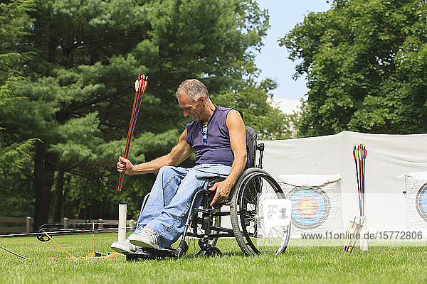 Mann im Rollstuhl auf einem Bogenschießplatz mit Pfeilen
