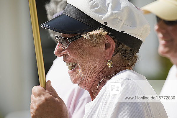 Seitenprofil einer älteren Frau  die einen Stock hält und lächelt