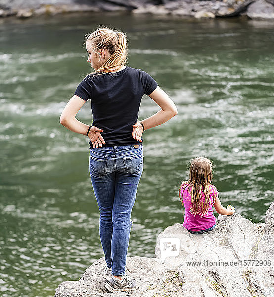 Zwei Schwestern verbringen Zeit miteinander am Rande eines Flusses; British Columbia  Kanada