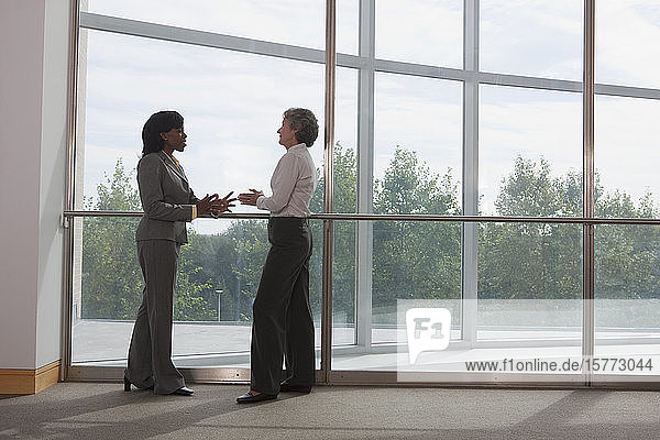 Two business women talking together in the corridor of a workplace