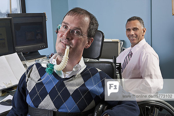 Businessmen in wheelchairs working in an office together