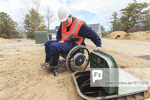 Mann im Rollstuhl arbeitet an Erdkabeln