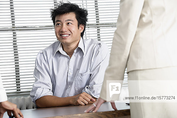 Blick auf einen lächelnden jungen Geschäftsmann in einem Büro.