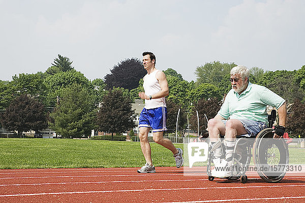 Young man racing with a handicapped senior man on the racetrack.