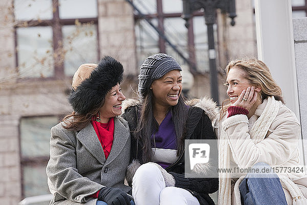 Drei Frauen sitzen draußen und reden miteinander