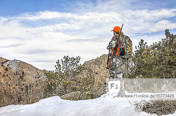 Jäger mit Tarnkleidung und Gewehr  der im Winter nach draußen schaut; Denver  Colorado  Vereinigte Staaten von Amerika