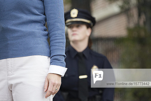 Eine Polizistin beobachtet eine Frau  die auf einer Straße geht.