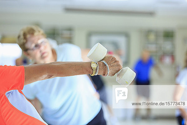 Trainerin hebt freie Gewichte in einem Fitnesskurs für Senioren
