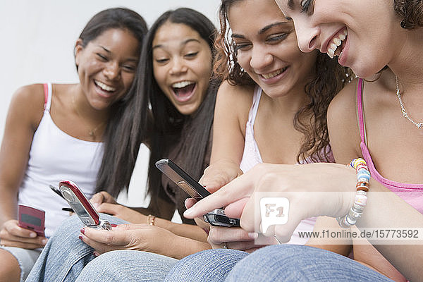 Vier Mädchen im Teenageralter benutzen Mobiltelefone