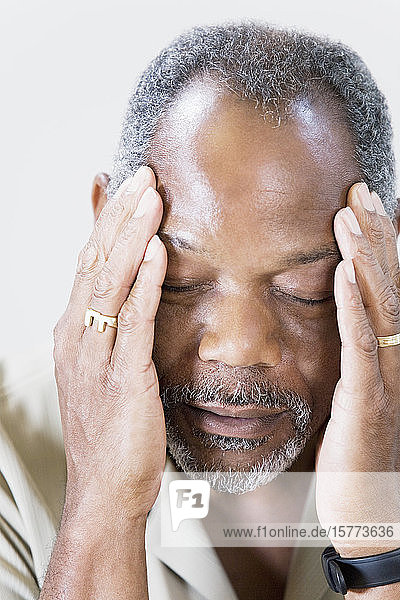 Nahaufnahme eines Mannes mittleren Alters  der unter Kopfschmerzen leidet
