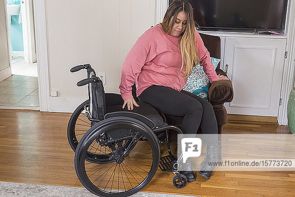 Frau mit Rückenmarksverletzung setzt sich in ihren Stuhl