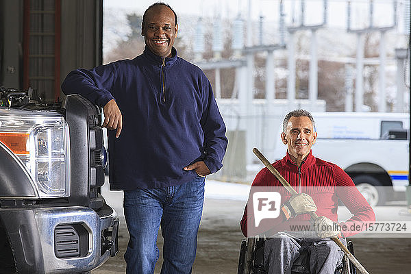 Vehicle mechanic and man in wheelchair with broom posing for a picture