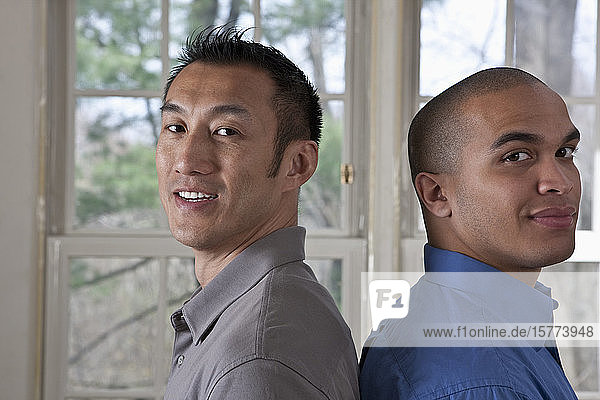 Porträt der Seitenansicht von zwei jungen Geschäftsleuten  die Rücken an Rücken stehen