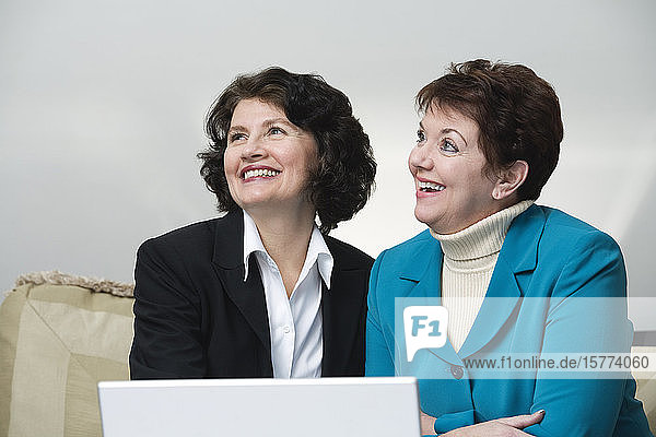 View of smiling business women sitting with a laptop.
